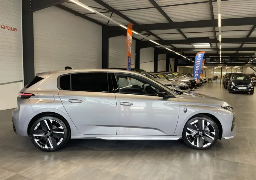 Peugeot 308 gris Artense vue de profil côté gauche, avec jantes alliage bi-tons et vitres surteintées en showroom.