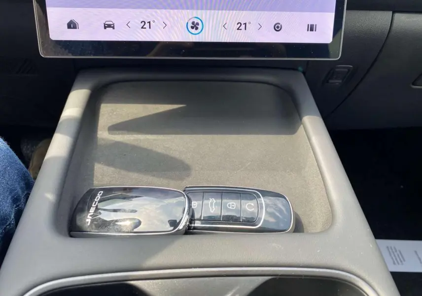 Gros plan sur la clé noire brillante JAECOO posée dans la console centrale grise du J7 blanc khaki.