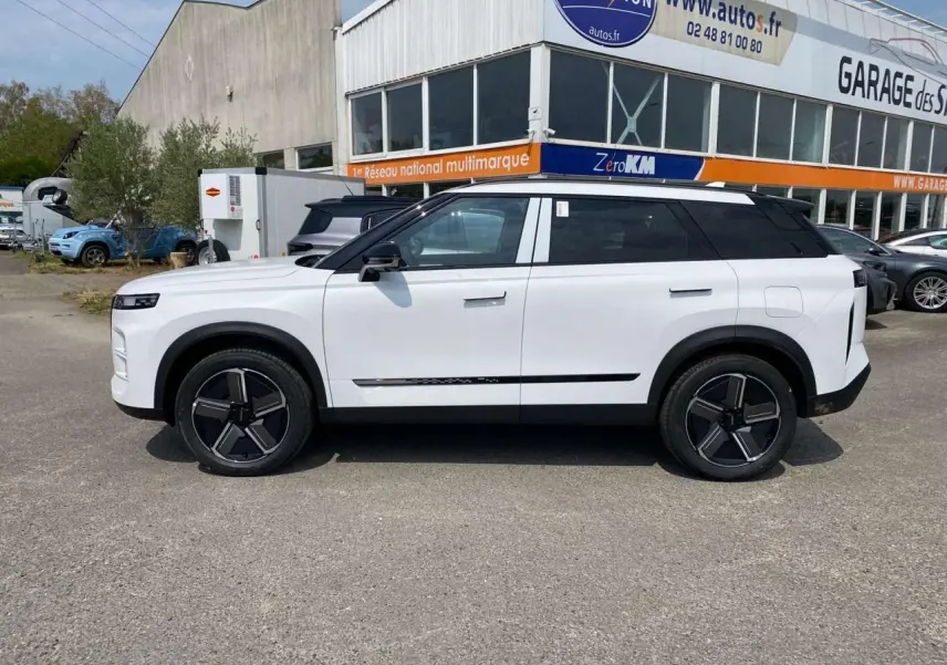 Vue de profil côté gauche du SUV JAECOO J7 blanc khaki avec jantes alliage noires et toit noir contrasté.