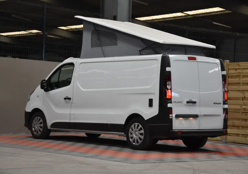 Renault Trafic Combi blanc vu de trois quarts arrière droit avec toit relevé et feux arrière allumés.
