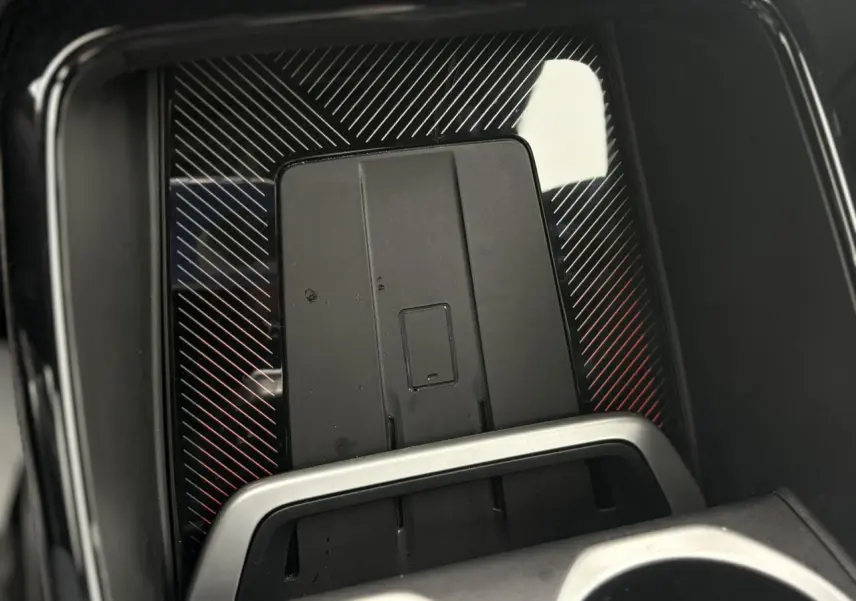 Gros plan sur la dalle de recharge par induction noire avec cadre argenté dans le BMW X1 blanc Mineral 2025.