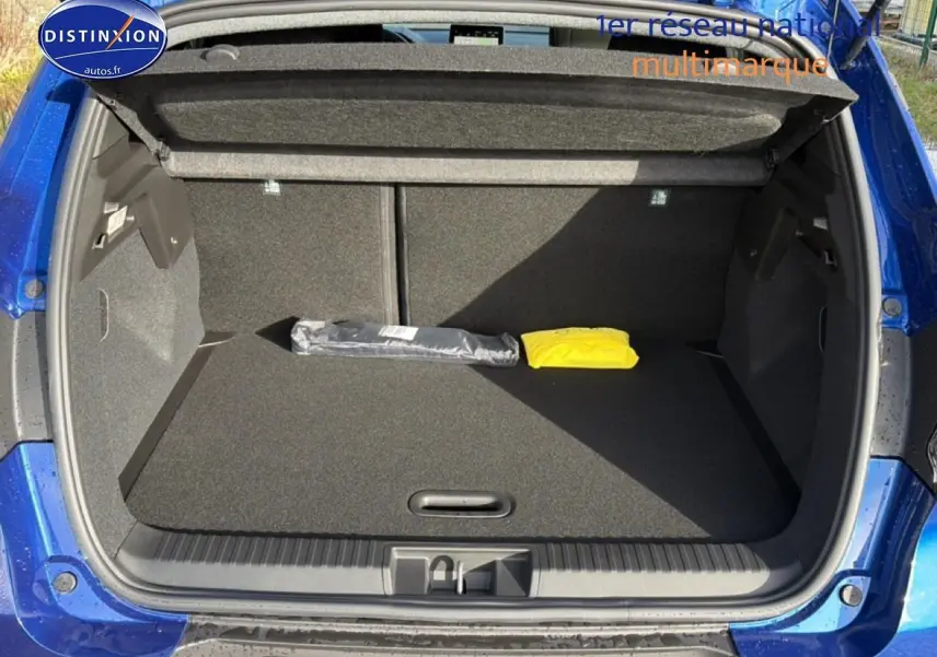 Coffre ouvert d'un Renault Captur Bleu Iron 2025, montrant un espace de rangement propre avec deux objets posés.