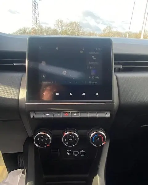 Vue centrale de l'écran tactile et des commandes de climatisation du tableau de bord de la Renault Clio gris 2021.