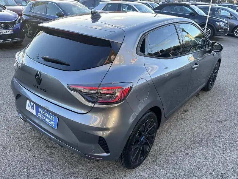 Vue 3/4 arrière droite d'une Renault Clio V gris schiste 2025 avec jantes noires et vitres teintées.