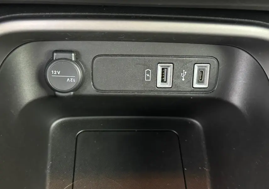 Vue rapprochée des ports USB et prise 12V intégrés dans la console centrale du Jeep Avenger noir 2025.
