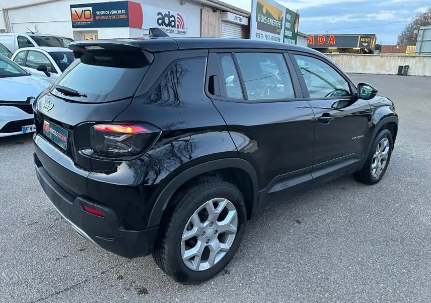 Jeep Avenger noir en vue 3/4 arrière droit, avec jantes alliage 17 pouces et feux arrière allumés.