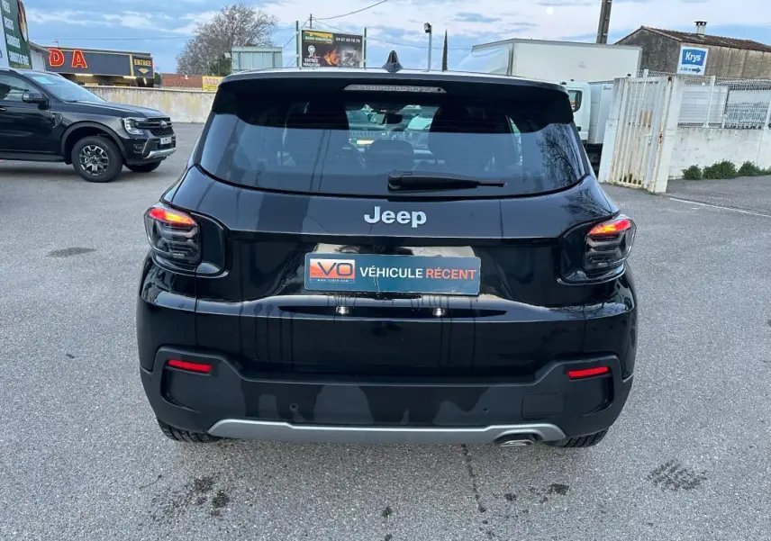 Vue arrière d'un Jeep Avenger noir 2025 avec feux allumés et plaque "Véhicule récent" sur parking extérieur.