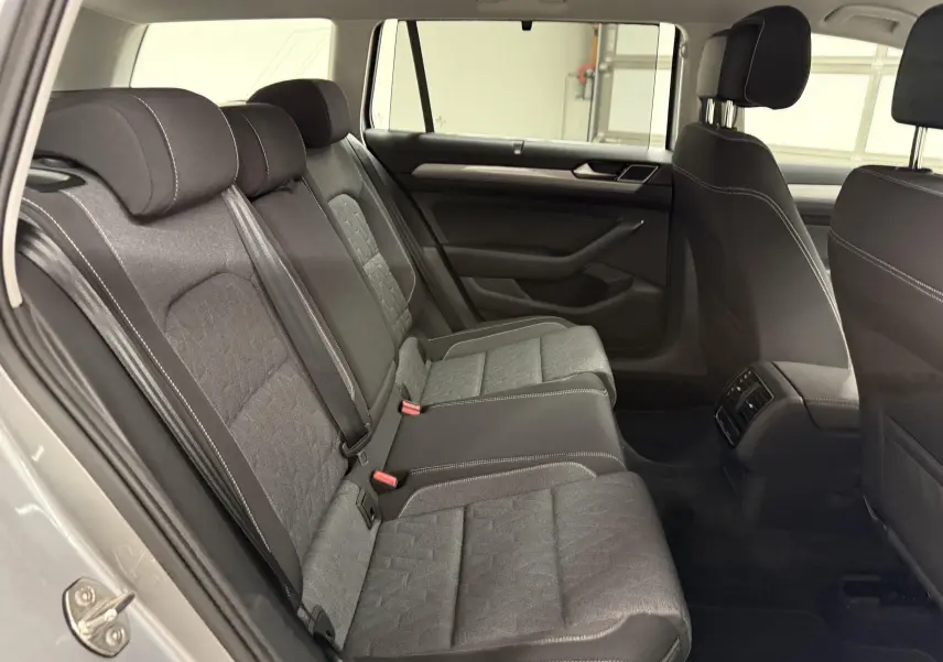 Vue intérieure sur les sièges arrière en tissu gris de la Volkswagen Passat SW 2024, côté gauche ouvert.