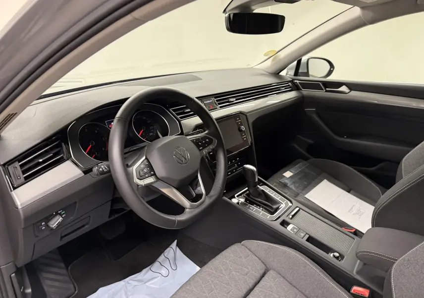 Vue intérieure côté conducteur de la Volkswagen Passat SW 2024, tableau de bord moderne avec volant multifonction et console centrale.