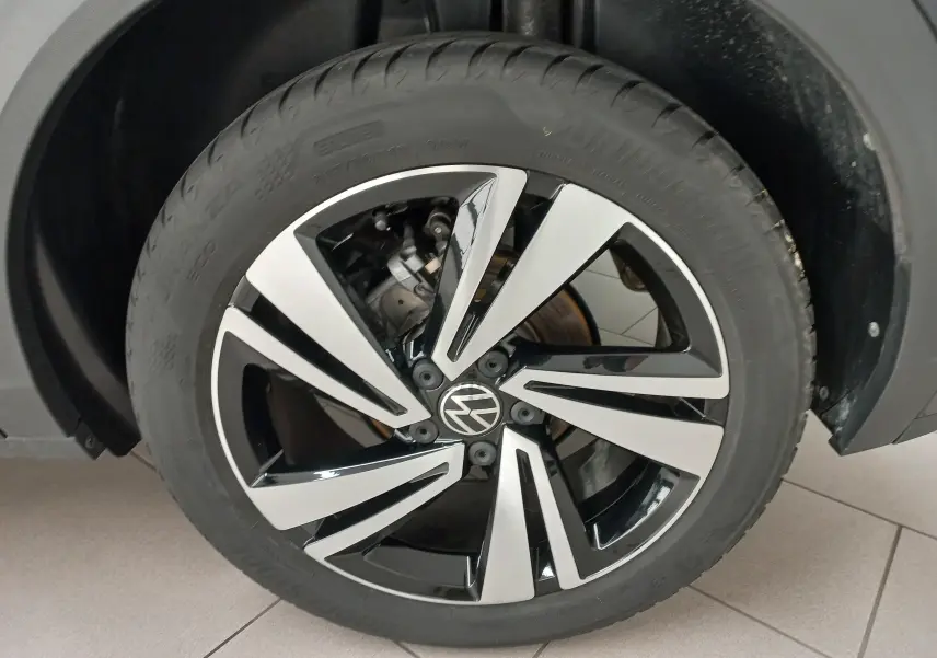 Gros plan sur la roue avant droite du Volkswagen T-Roc 1.5 TSI 150 DSG7 R-Line, jante alliage bicolore noir et argent.