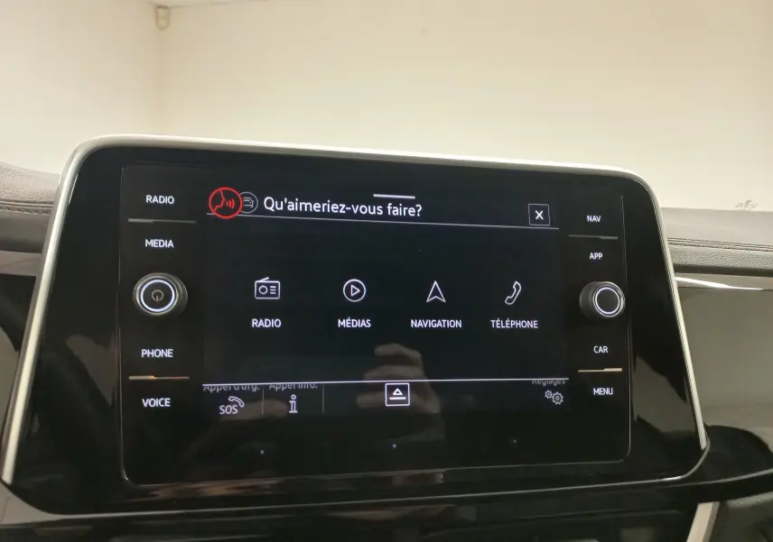 Écran tactile central du Volkswagen T-Roc 2025 avec interface vocale affichée, entouré de commandes physiques.