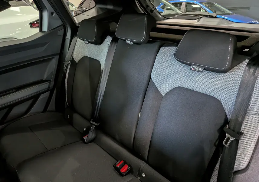 Vue intérieure sur la banquette arrière du Dacia Duster 2026, tissu bicolore noir et gris avec appuie-têtes intégrés.