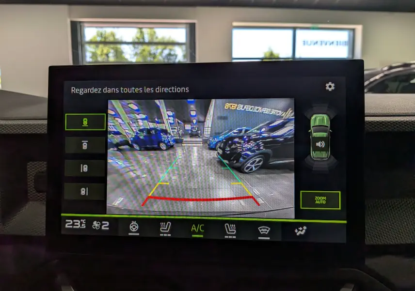 Vue de l'écran multimédia du Dacia Duster gris schiste montrant la caméra de recul avec lignes de guidage colorées.