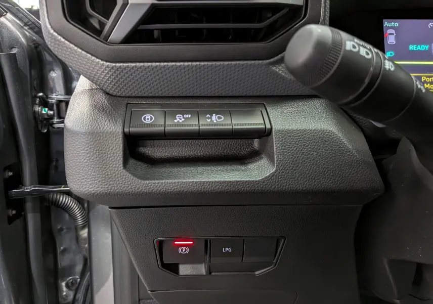 Gros plan sur les commandes intérieures du Dacia Duster gris schiste 2026, avec bouton frein à main électronique et mode GPL.