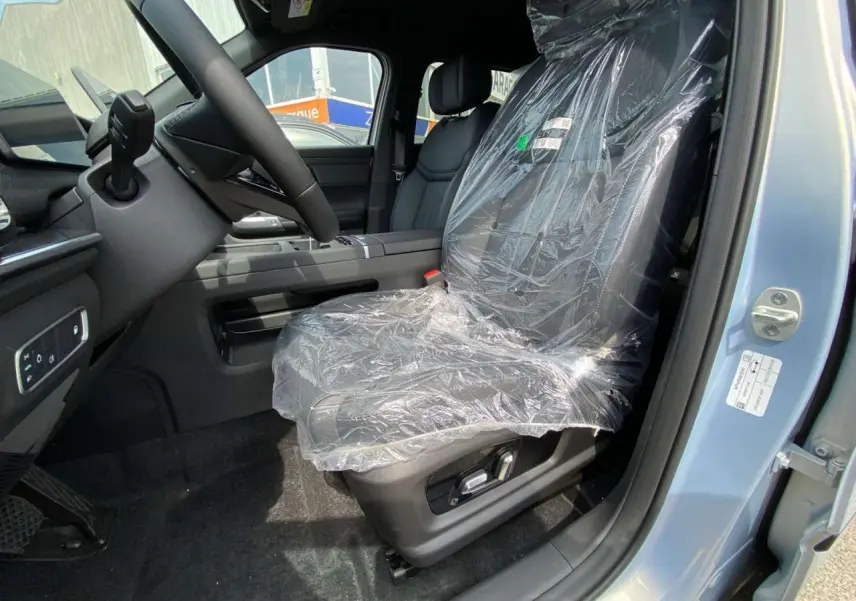 Vue intérieure côté conducteur du JAECOO J7 1.5 SHS-P argent Moonlight, siège avant protégé par film plastique.