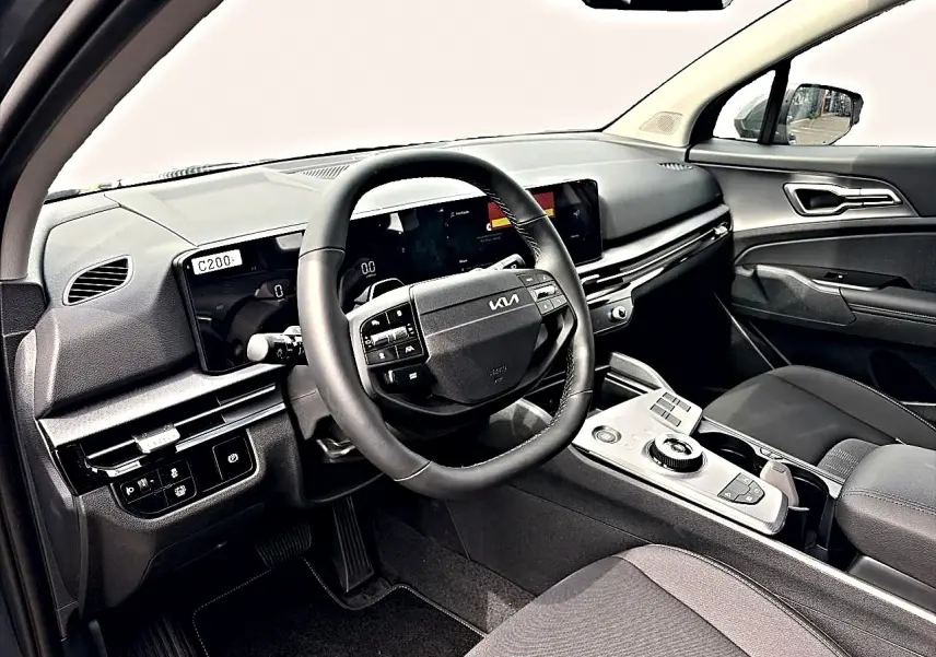 Vue intérieure côté conducteur du tableau de bord et volant cuir noir du Kia Sportage 1.6 hybride 239 gris eclipse.