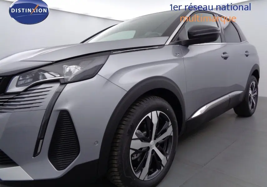 Gros plan sur la roue avant gauche et l'aile gris Artense métallisé du Peugeot 3008 GT 2023 avec jante bi-ton distinctive.