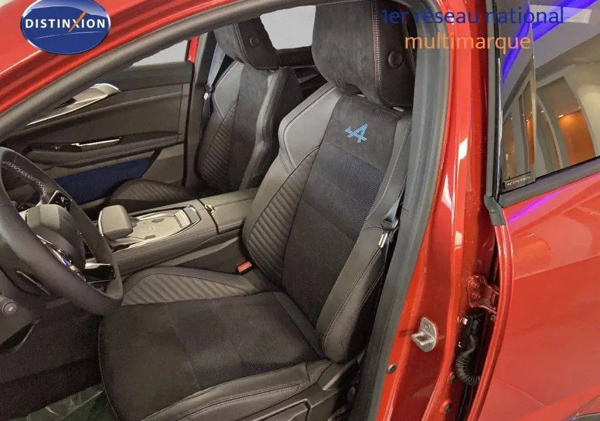 Intérieur côté conducteur d'une Renault Rafale rouge flamme, sièges noirs avec logo Alpine bleu brodé sur appuie-tête.