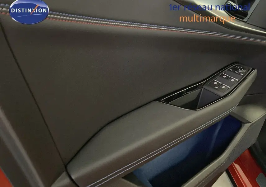 Détail de la porte côté conducteur du Renault Rafale rouge flamme avec surpiqûres bleues et commandes de vitres.