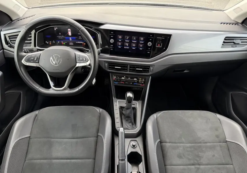 Intérieur avant de la Volkswagen Polo 2025 avec tableau de bord moderne, volant cuir multifonction et sellerie microfleece noire.