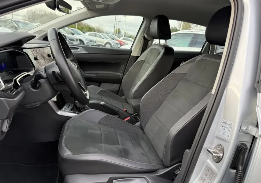 Vue intérieure côté conducteur de la Volkswagen Polo 2025 argent, sièges Microfleece ArtVelours noirs et tableau de bord moderne.