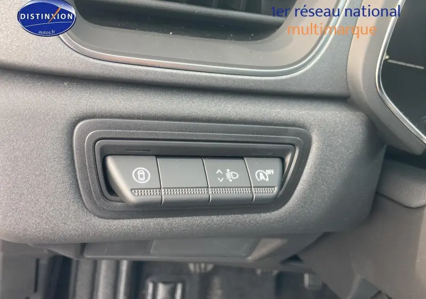 Gros plan sur les commandes de réglage des phares et verrouillage, tableau de bord noir Renault Captur Bleu Iron 2025.