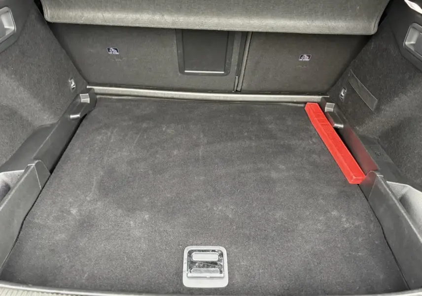 Coffre spacieux du DS7 1.6 E-Tense gris laqué, vue intérieure montrant le tapis noir et un triangle de sécurité rouge.