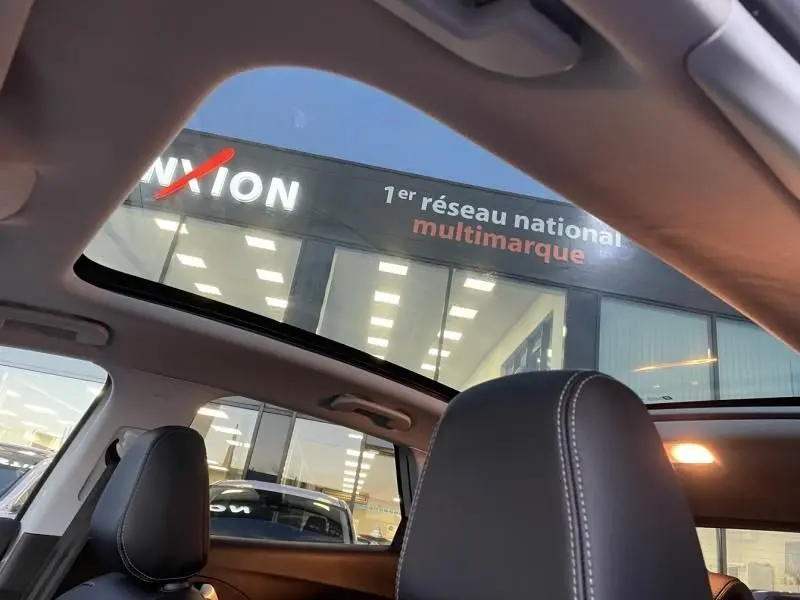 Vue intérieure du toit ouvrant panoramique du Opel Grandland X blanc toit noir, avec sièges avant en cuir noir visibles.