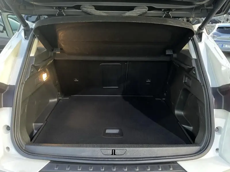 Coffre ouvert vu de l'arrière d'un Opel Grandland X blanc avec toit noir, montrant un espace de chargement vide et propre.