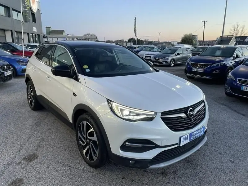Opel Grandland X blanc avec toit noir, vue 3/4 avant droit, calandre noire et jantes alliage distinctives.