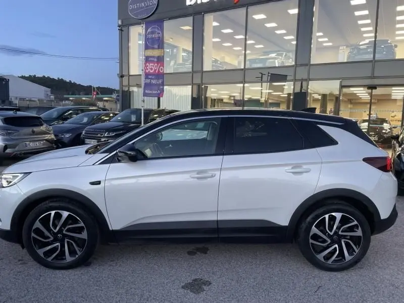 Vue de profil côté gauche d’un Opel Grandland X blanc avec toit noir, roues alliage et détails noirs contrastants.