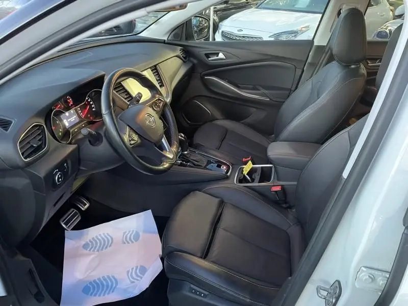 Vue intérieure côté conducteur de l’Opel Grandland X 2019 blanc, avec sièges cuir noirs et tableau de bord moderne.