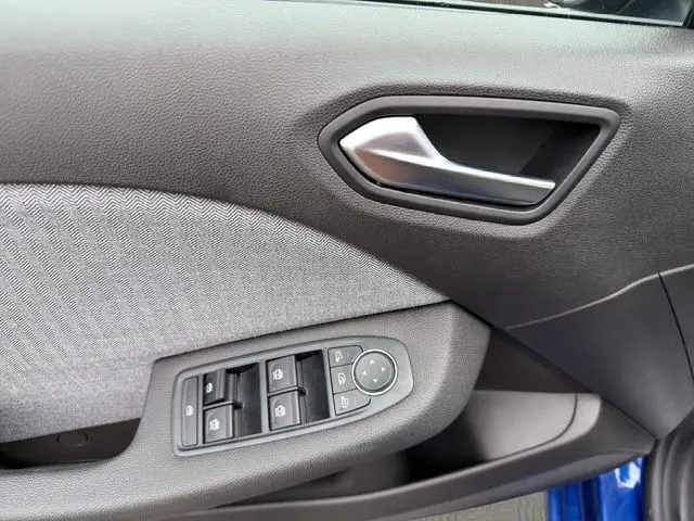 Gros plan sur la porte côté gauche de la Renault Clio V bleu Iron, montrant la poignée intérieure et les commandes des vitres électriques.