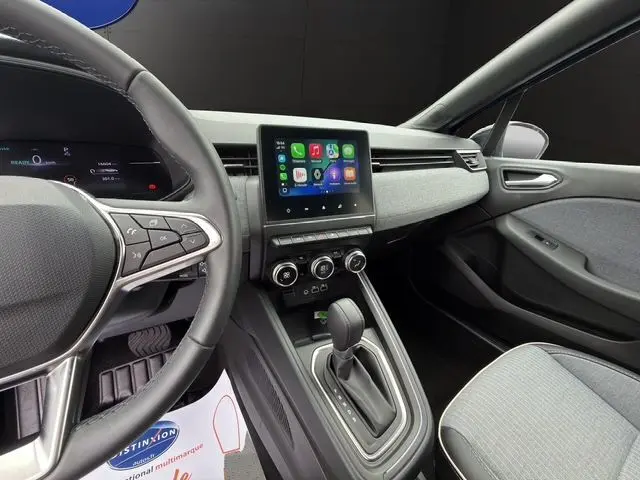 Vue intérieure côté conducteur de la Renault Clio V E-Tech, tableau de bord avec écran tactile et volant textile gris.