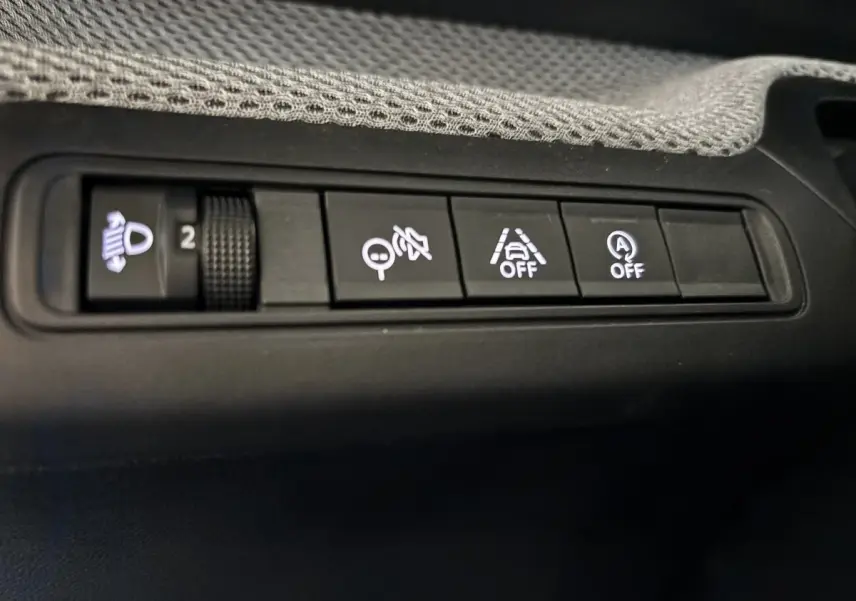 Gros plan sur les boutons de commande du tableau de bord de la Citroën C3 100 BVM PLUS, intérieur noir.