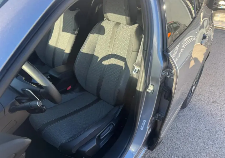 Vue côté gauche intérieur du siège conducteur gris du Peugeot 2008 Hybrid 136 e-DCS6 Allure 2024 avec porte ouverte.