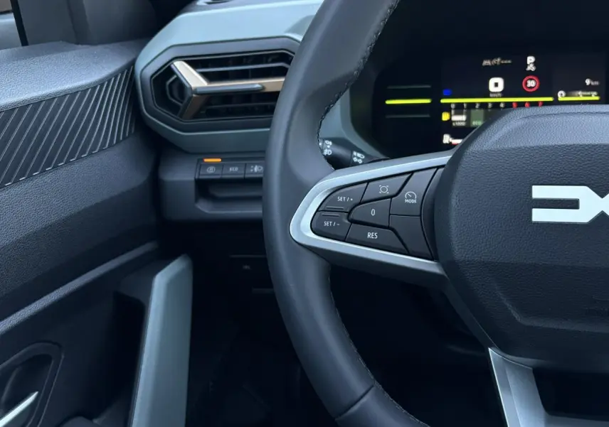 Vue rapprochée du volant et tableau de bord digital du Dacia Duster 2026, intérieur noir avec commandes au volant.