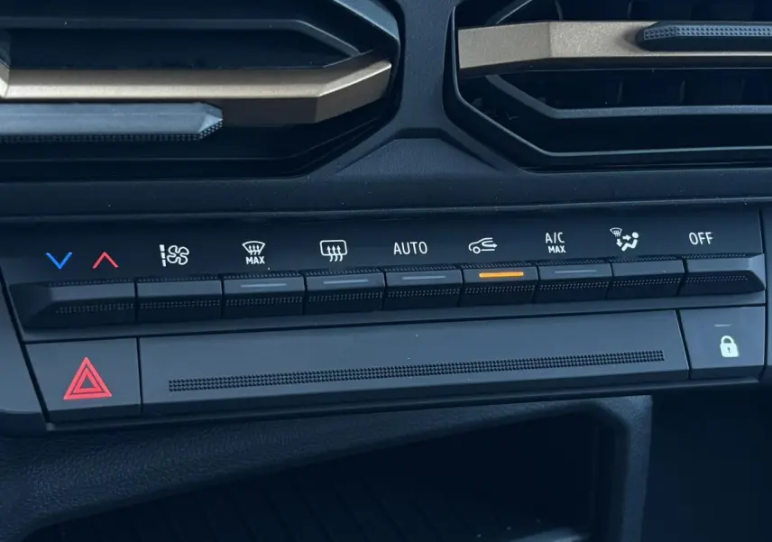 Gros plan sur la console centrale du Dacia Duster 2026 gris schiste, montrant les commandes de climatisation automatique.