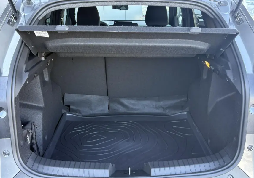 Coffre ouvert vu de l'arrière du Dacia Duster Gris Schiste 2026, avec tapis de coffre noir et habillage intérieur sombre.