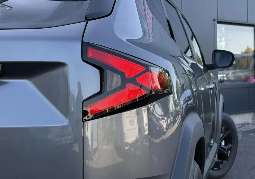 Gros plan sur le feu arrière droit du Dacia Duster 2026 gris schiste, mettant en valeur la finition moderne et les jantes noires.
