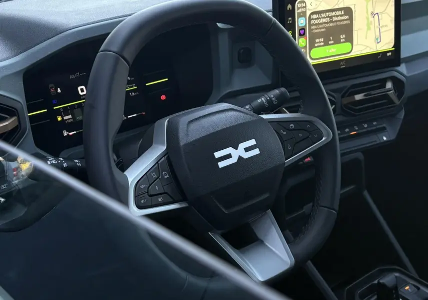Vue rapprochée de l’intérieur du Dacia Duster 2026, volant multifonctions et écran tactile central avec navigation visible.