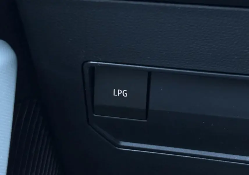 Gros plan sur le bouton LPG noir dans l'habitacle du Dacia Duster gris, indiquant la bicarburation GPL.