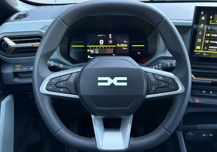 Vue rapprochée du volant noir du Dacia Duster 2026 avec tableau de bord digital et écran tactile central.