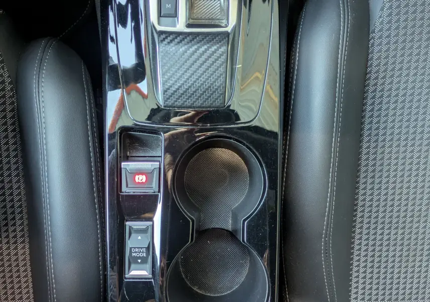Vue plongeante sur la console centrale noire brillante du Peugeot 2008 GT, avec levier de vitesses automatique et porte-gobelets.