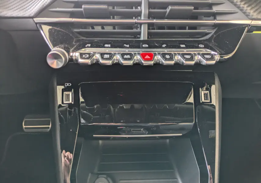 Vue rapprochée de la console centrale noire brillante du Peugeot 2008 GT 2022 avec commandes tactiles et ports USB visibles.