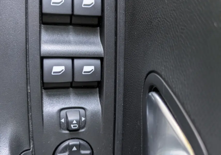 Gros plan sur les commandes de lève-vitres et réglage des rétroviseurs côté conducteur du Peugeot 2008 GT blanc nacré.