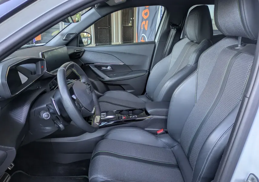 Vue intérieure côté conducteur du Peugeot 2008 GT 2022, sièges noirs avec surpiqûres vertes et tableau de bord moderne.