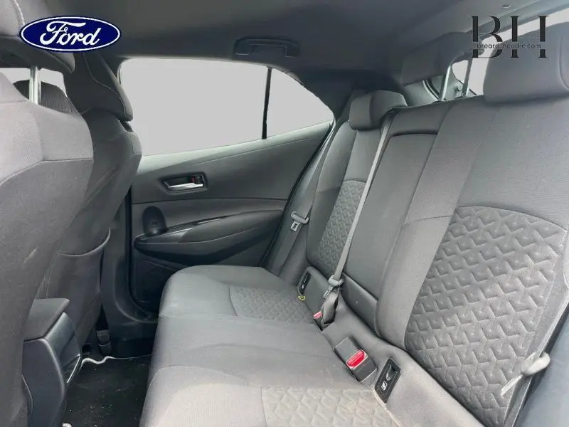 Vue intérieure arrière côté droit de la Toyota Corolla 184h Dynamic Business 2022 avec sièges tissu noir et ceintures grises