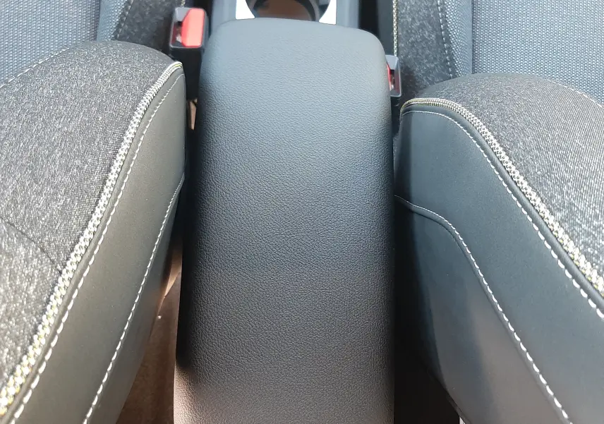 Vue plongeante sur l'accoudoir central en cuir noir et les sièges tissu gris du Renault Captur II Ph.2 2025.