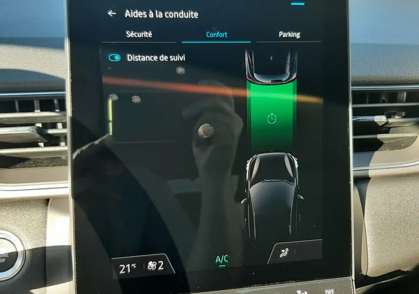 Écran tactile central du Renault Captur bleu Iron 2025 montrant l'assistance à la conduite avec affichage de la distance de suivi.